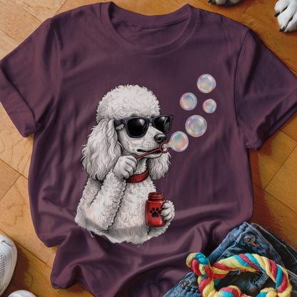 A plum-colored t-shirt features a graphic of a white poodle wearing sunglasses and blowing bubbles.