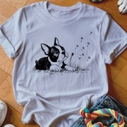 A white crewneck t-shirt featuring a black graphic of a Boston terrier puppy watching dandelion seeds blow away.
