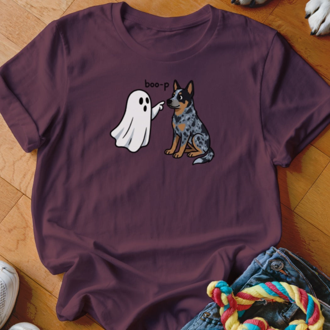 A ghost playfully boops a blue heeler dog on a maroon t-shirt.