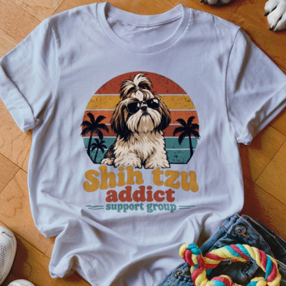A white t-shirt featuring a retro graphic of a Shih Tzu wearing sunglasses before palm trees and a sunset.