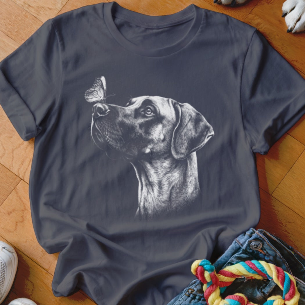 A dark grey t-shirt featuring a white sketch of a dog looking at a butterfly.