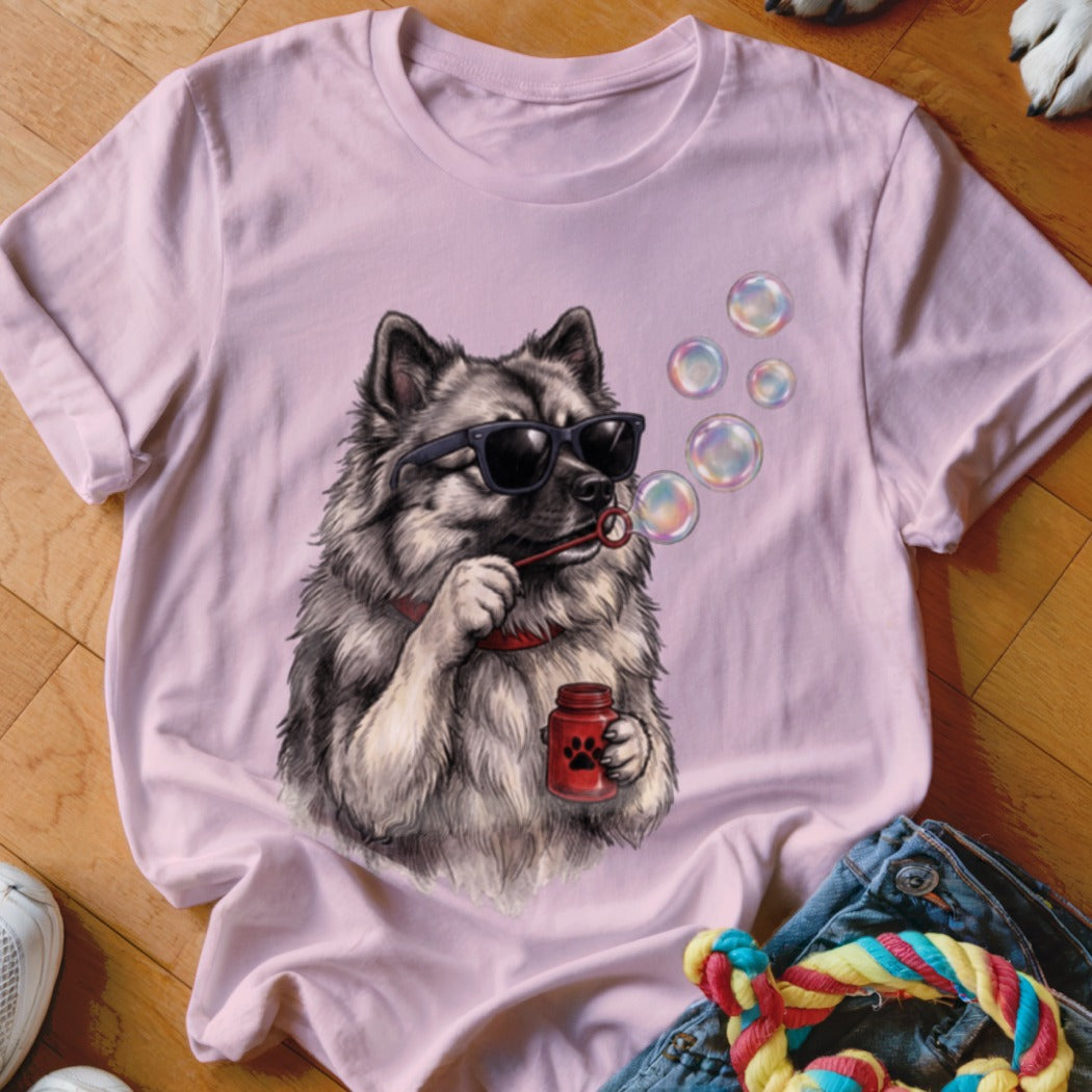 Light pink t-shirt featuring a graphic of a fluffy dog wearing sunglasses and blowing soap bubbles.