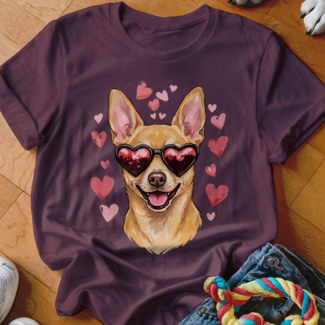 A maroon t-shirt featuring a cartoon chihuahua wearing heart-shaped sunglasses surrounded by floating pink hearts.