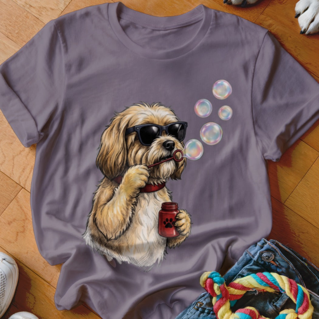 A grey crewneck t-shirt featuring a graphic of a shaggy blonde dog wearing sunglasses and blowing bubbles.