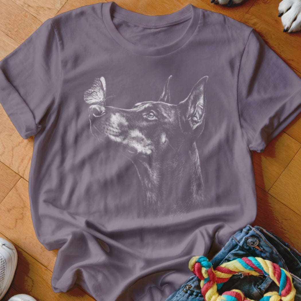 A purple crewneck t-shirt featuring a white line drawing of a Doberman pinscher looking at a butterfly.