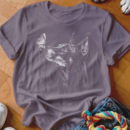 A purple crewneck t-shirt featuring a white line drawing of a Doberman pinscher looking at a butterfly.