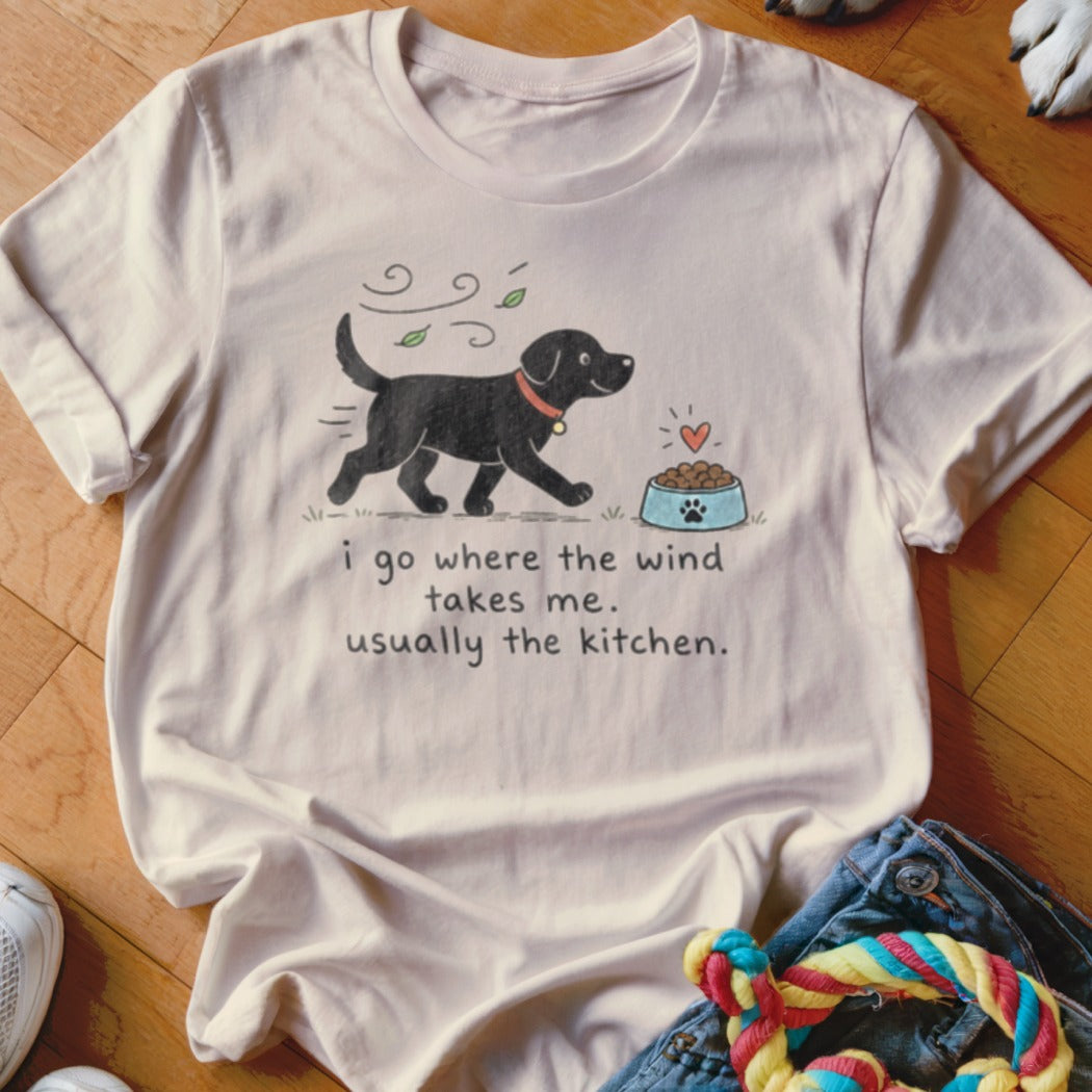 T-shirt with black dog illustration and text "i go where the wind takes me, usually the kitchen."