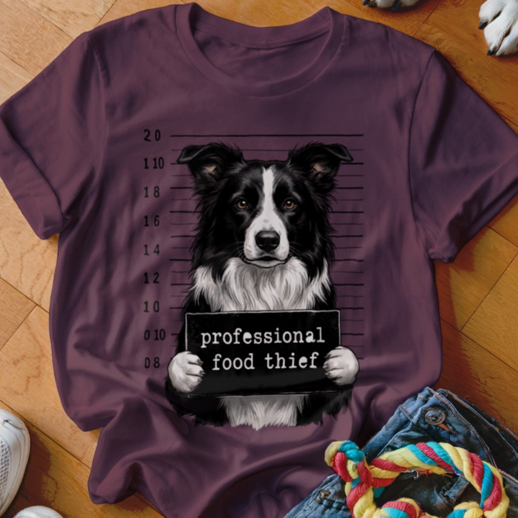 Border Collie mugshot with text "professional food thief" on a maroon t-shirt.