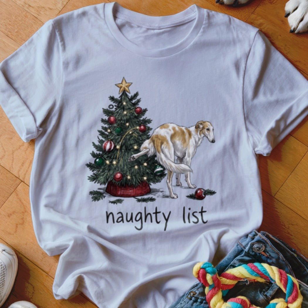 A white t-shirt featuring a graphic of a dog lifting its leg on a Christmas tree with the text naughty list underneath.