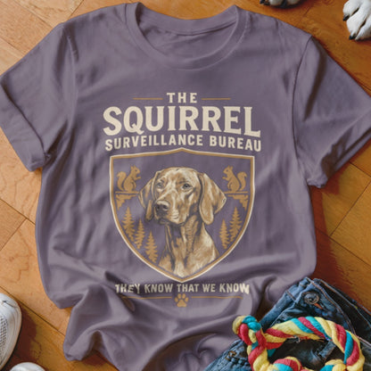 A grey t-shirt featuring the text "The Squirrel Surveillance Bureau" and a crest with a dog and squirrels.