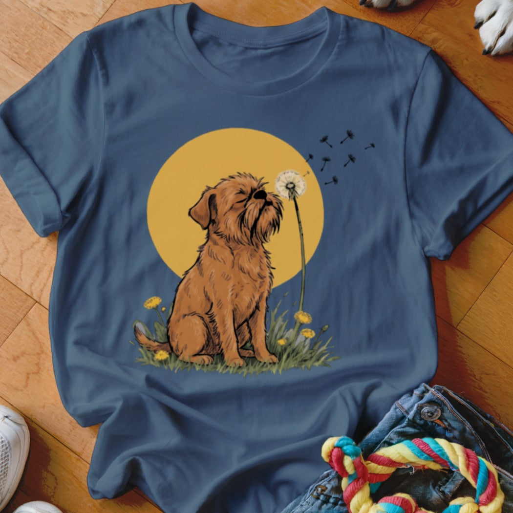 A blue crewneck t-shirt featuring an illustration of a brown scruffy dog sitting before a yellow sun and dandelion.