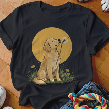 A black short-sleeved t-shirt featuring a golden retriever puppy sniffing a dandelion against a yellow circle.