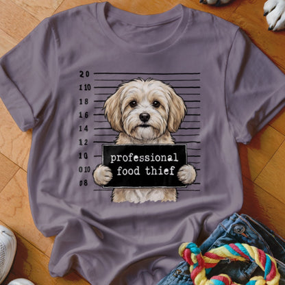 T-shirt featuring a mugshot of a fluffy dog holding a sign that reads "professional food thief".
