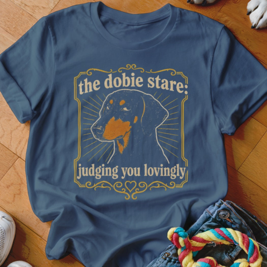 Dachshund graphic on a blue t-shirt with text "the dobie stare: judging you lovingly".