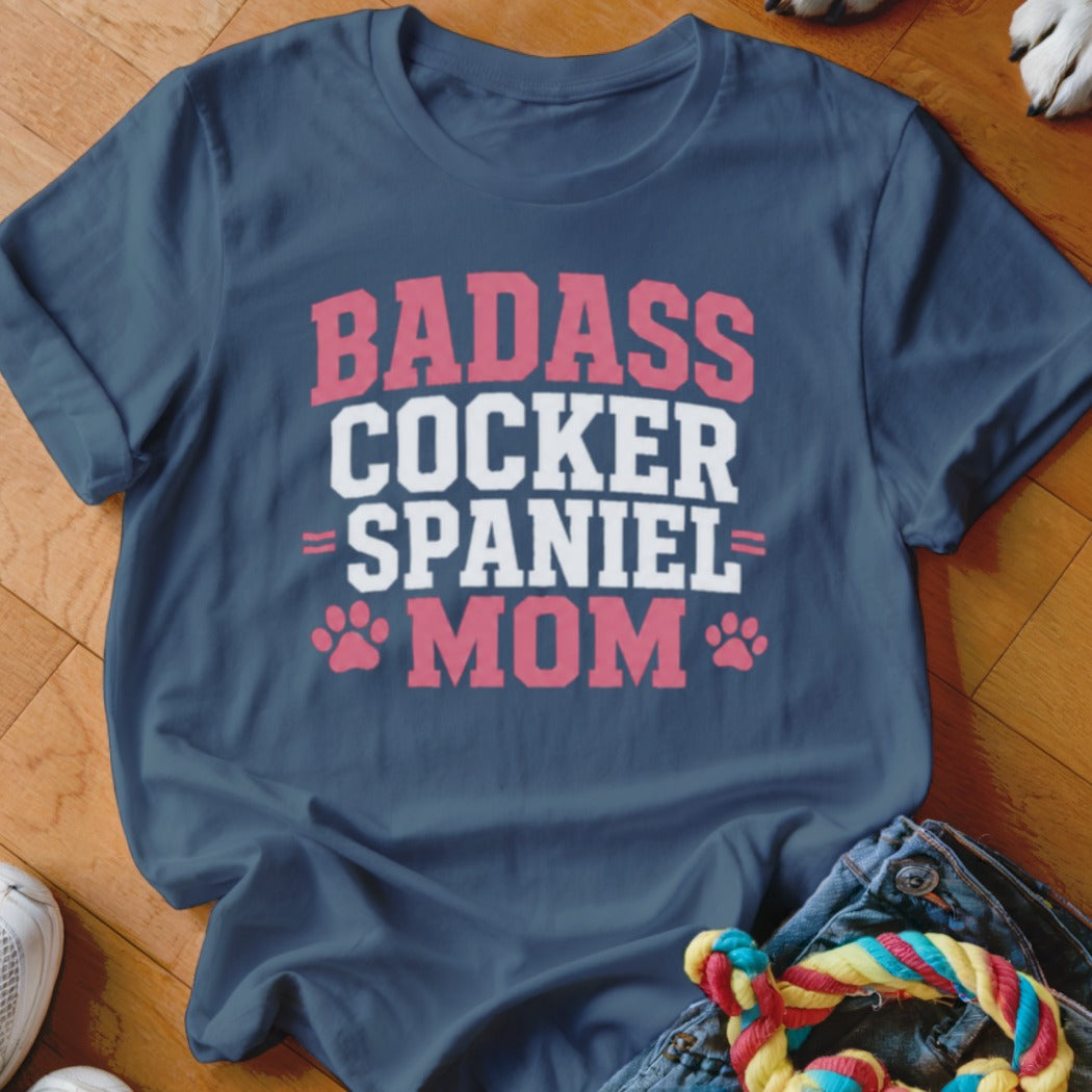 Navy t-shirt with pink and white text reading "BADASS COCKER SPANIEL MOM" and paw prints.