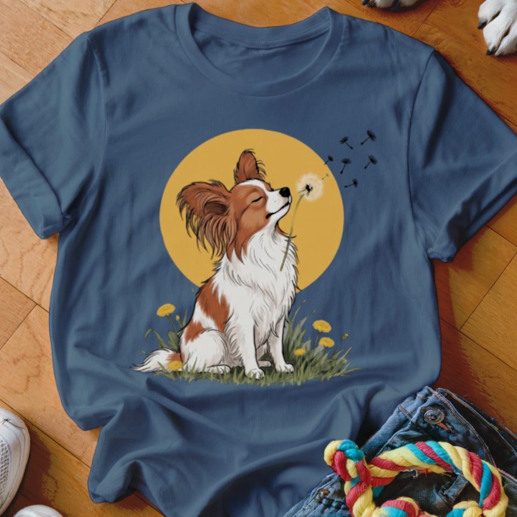A dark blue t-shirt features a graphic of a brown and white dog blowing a dandelion seed head.