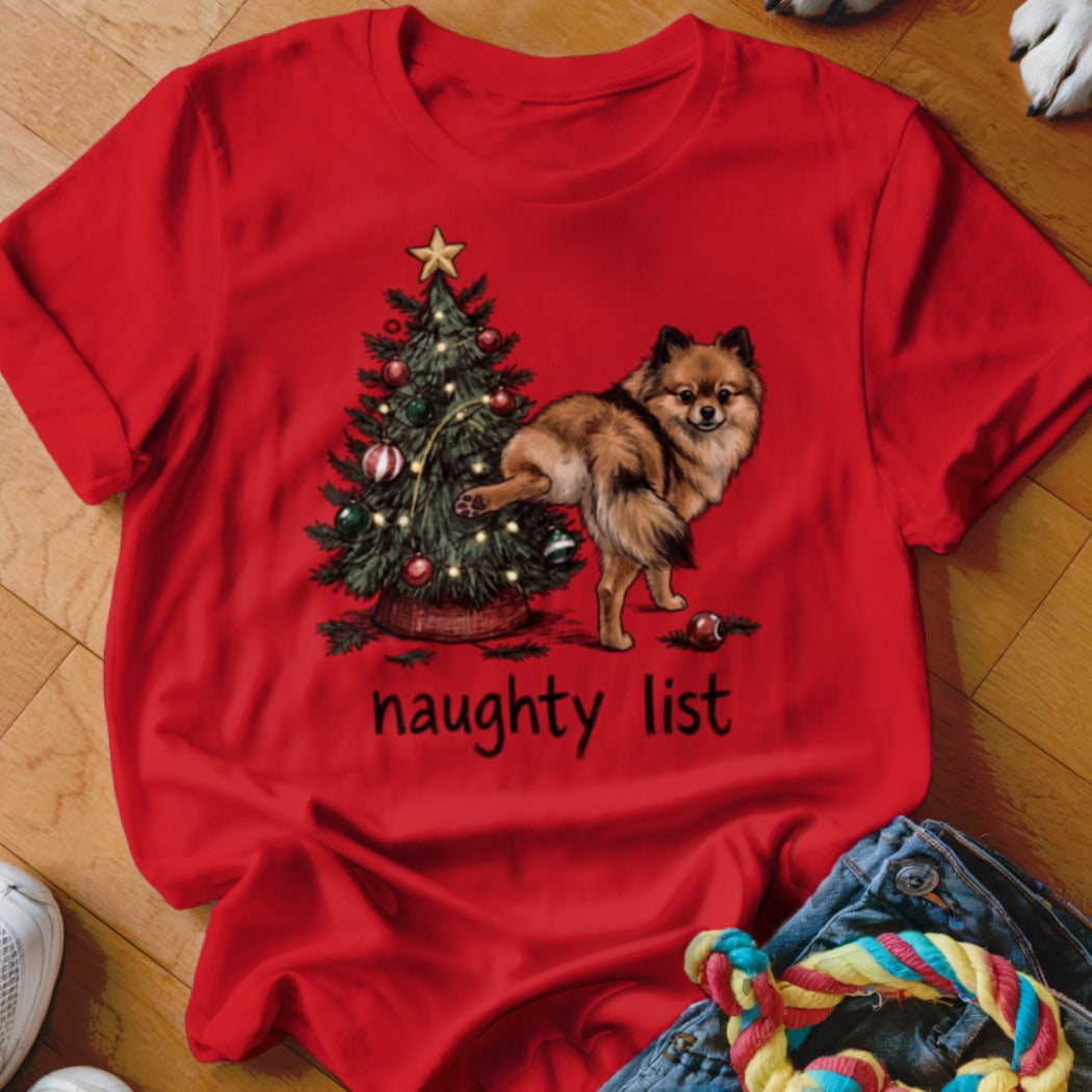 Red t-shirt with a Pomeranian dog next to a Christmas tree and the text "naughty list".