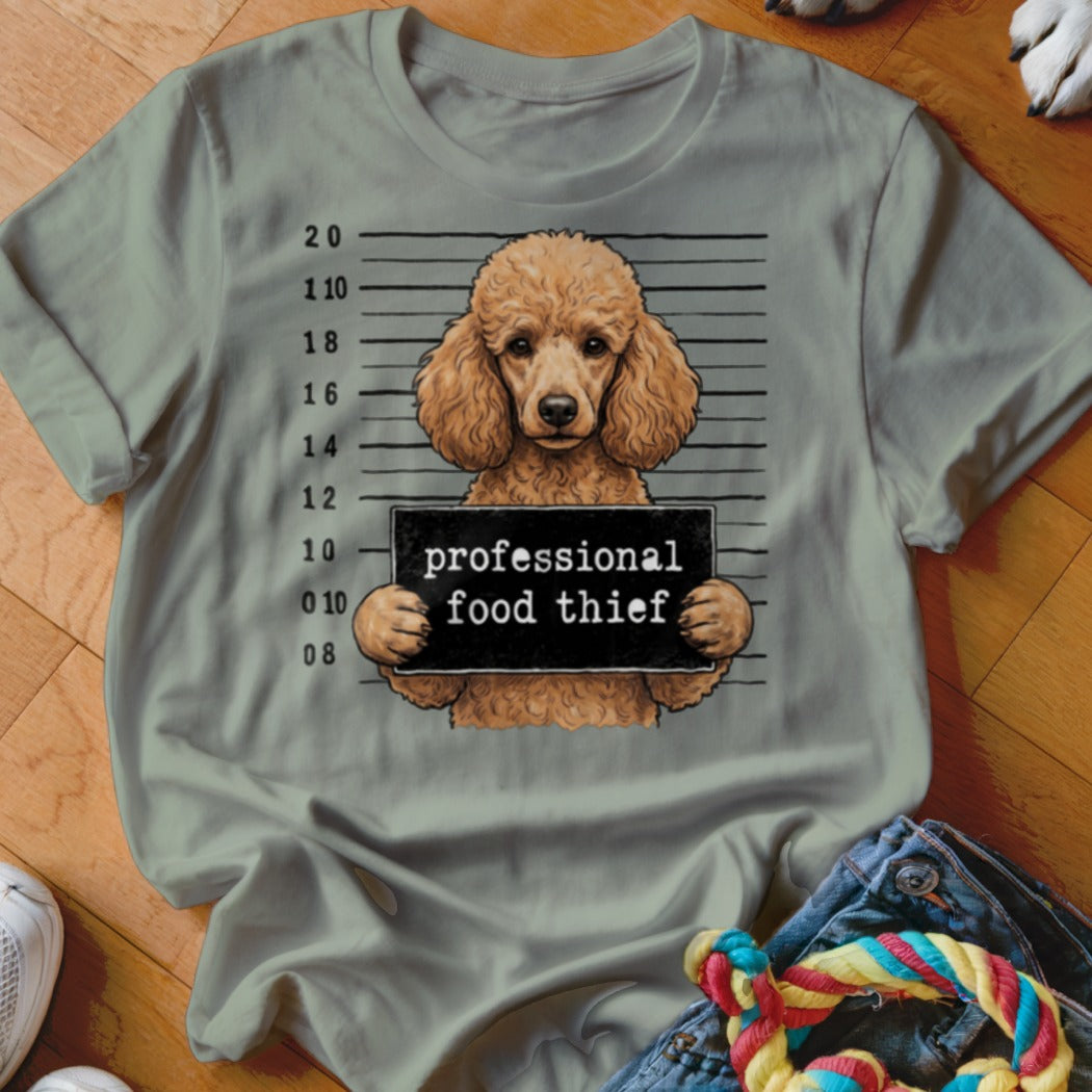 Poodle mugshot with "professional food thief" sign on a light green t-shirt.