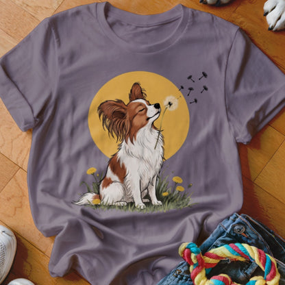 Gray t-shirt featuring an illustration of a Papillon dog blowing dandelion seeds against a yellow circle background.