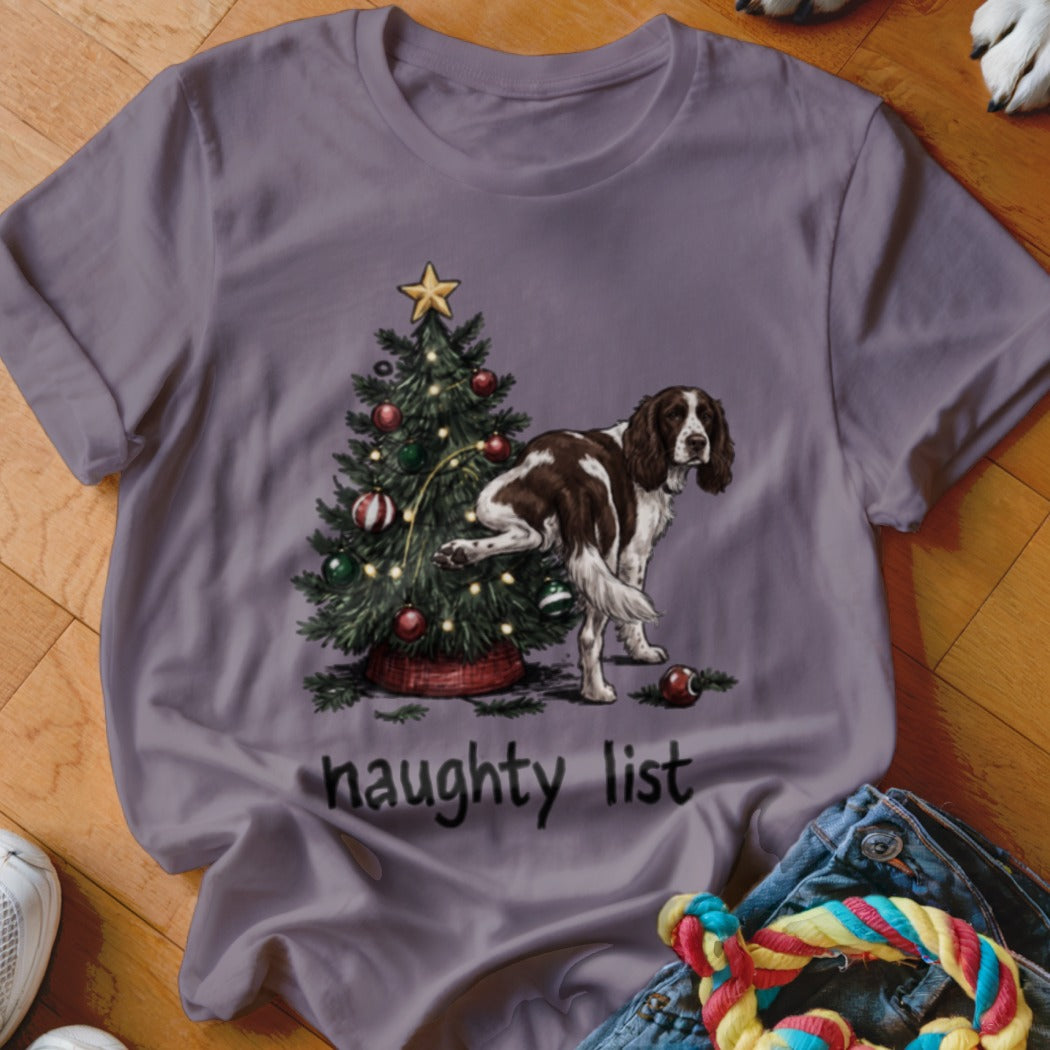 English Springer Spaniel lifting leg on Christmas tree with "naughty list" text.