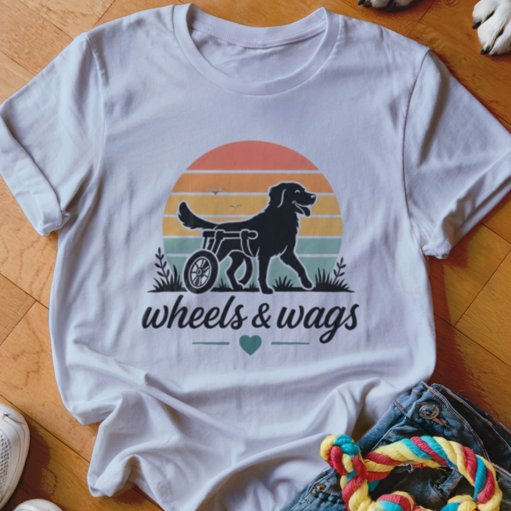 Black dog in a wheelchair graphic with "wheels & wags" text on a white t-shirt.
