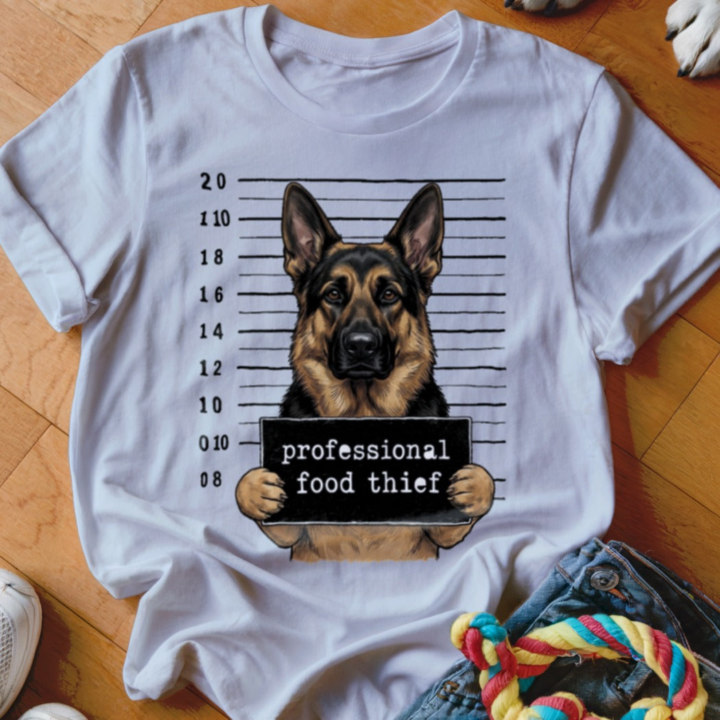 German Shepherd mugshot with "professional food thief" sign on white t-shirt.