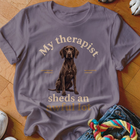 Purple t-shirt with a seated brown dog and text "My therapist sheds an awful lot."