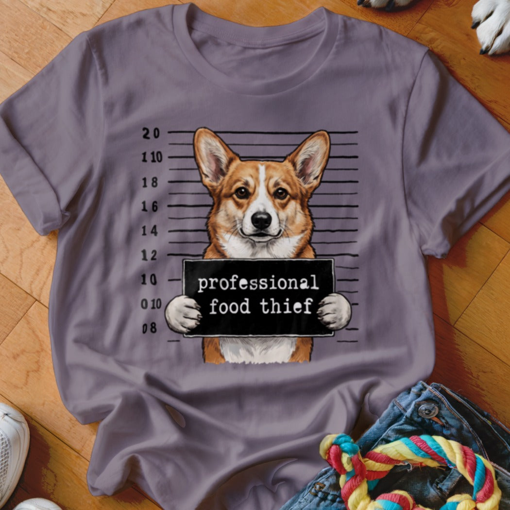 Corgi in mugshot holding a sign that says "professional food thief".