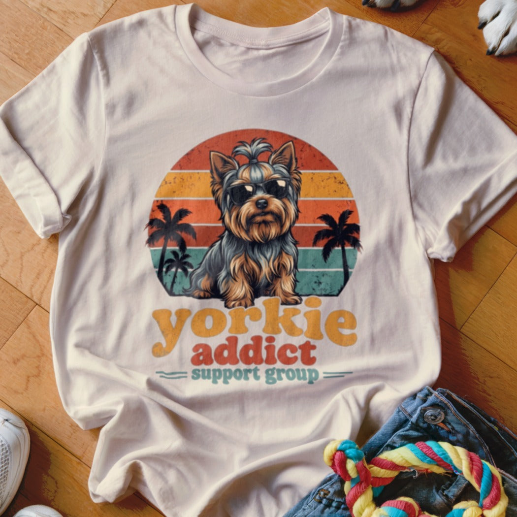 Cream t-shirt with a vintage graphic of a Yorkie wearing sunglasses in front of a sunset, reading Yorkie Addict Support Group.