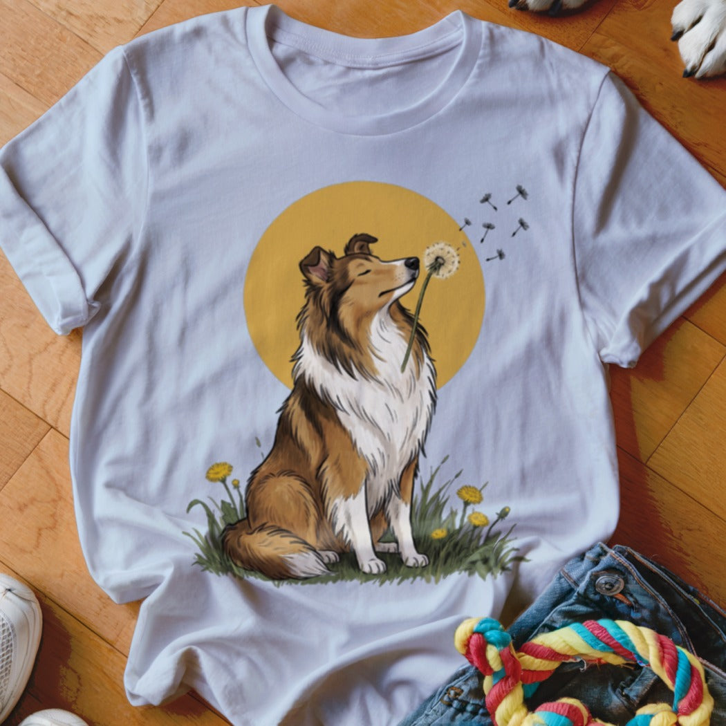 A white crewneck t-shirt featuring an illustration of a collie dog sniffing a dandelion against a yellow circle background.