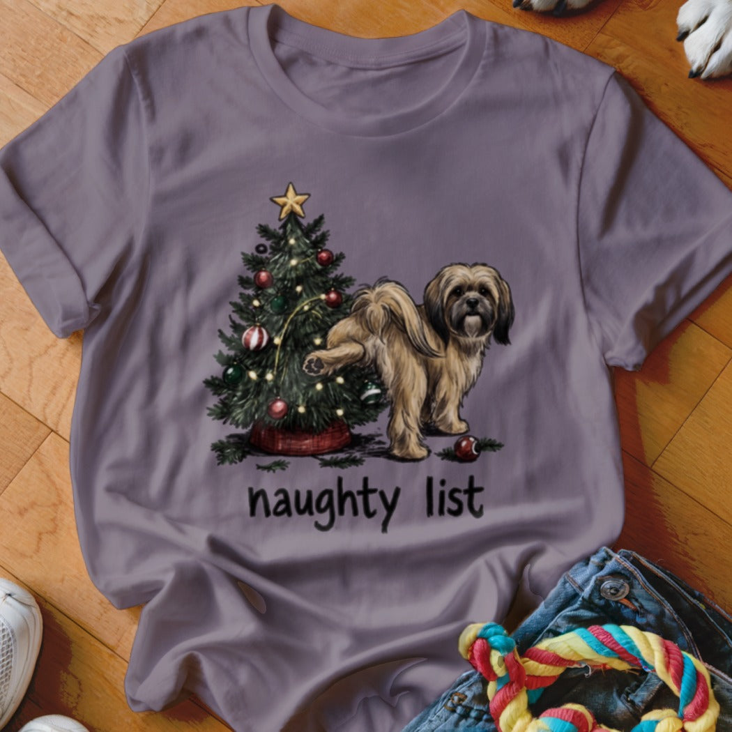 Shih Tzu dog by Christmas tree with "naughty list" text on a purple t-shirt.