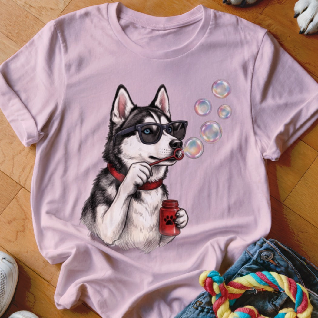 A light pink t-shirt features a graphic of a husky wearing sunglasses and blowing bubbles.