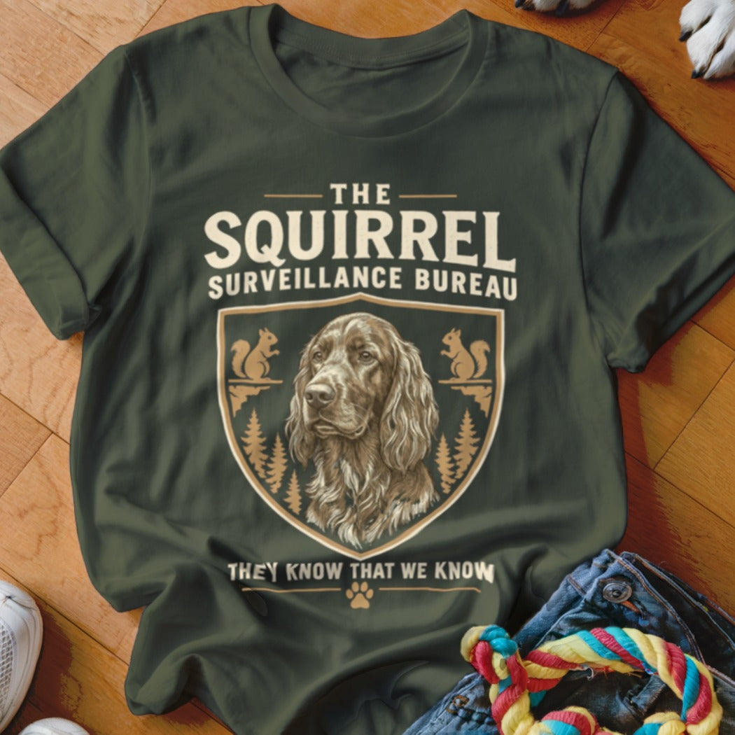 Dark green t-shirt with a vintage-style crest graphic featuring an Irish Setter dog, squirrels, and the text The Squirrel Surveillance Bureau.