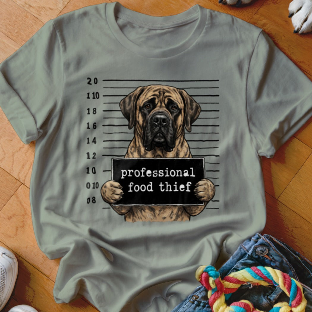 Mastiff dog mugshot holding "professional food thief" sign on a t-shirt.