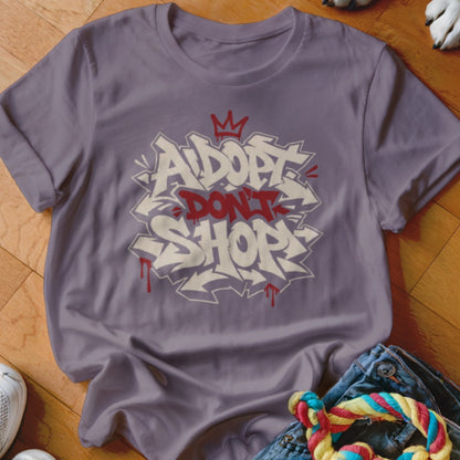 Purple t-shirt with "Adopt Don't Shop" graffiti style text and a crown graphic.
