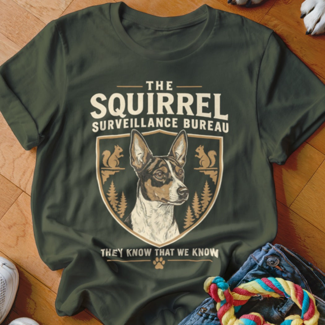A dark green t-shirt with a graphic of a dog, squirrels, and the text The Squirrel Surveillance Bureau.