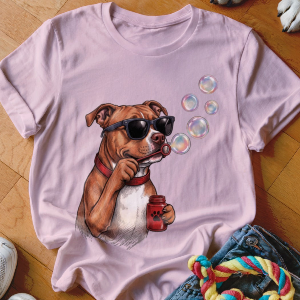 A light pink t-shirt featuring a graphic of a brown dog wearing sunglasses and blowing bubbles.