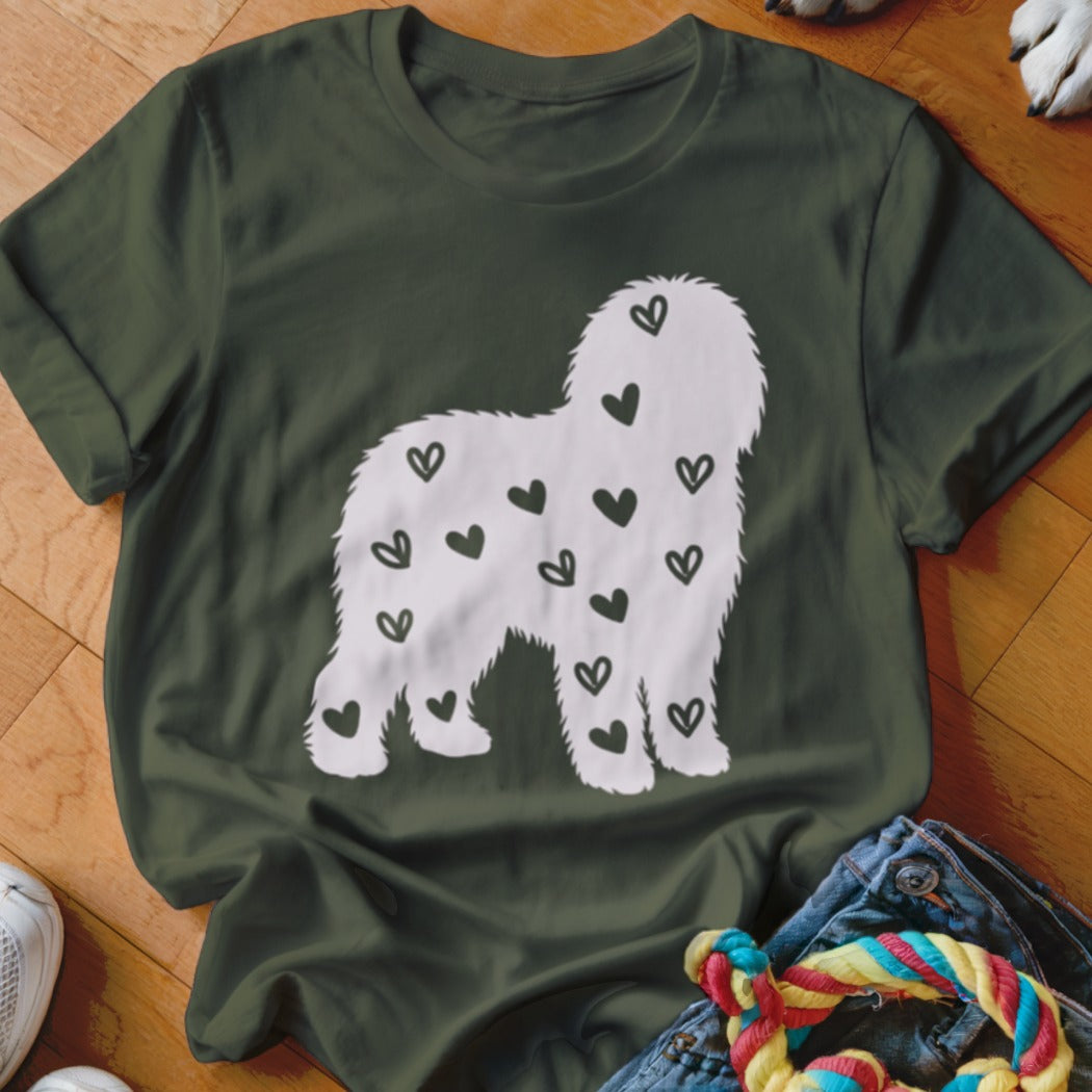 Green t-shirt with white silhouette of a fluffy dog covered in black hearts.