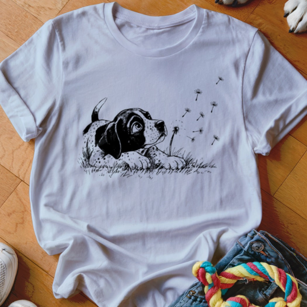White crewneck t-shirt featuring a black ink illustration of a puppy watching floating dandelion seeds.