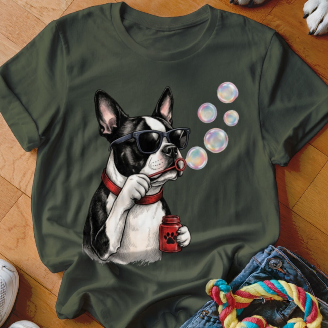 An olive green t-shirt featuring a graphic of a Boston Terrier wearing sunglasses and blowing soap bubbles.