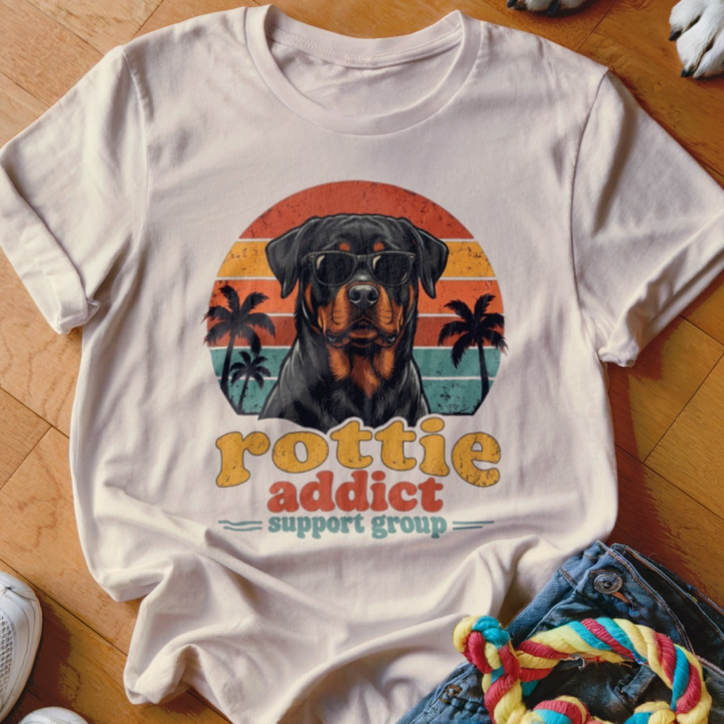 Light beige t-shirt featuring a retro graphic of a Rottweiler in sunglasses against a sunset.