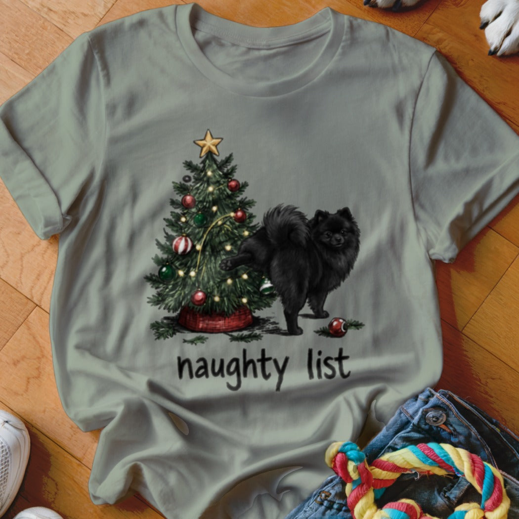 Black Pomeranian dog near Christmas tree with "naughty list" text.