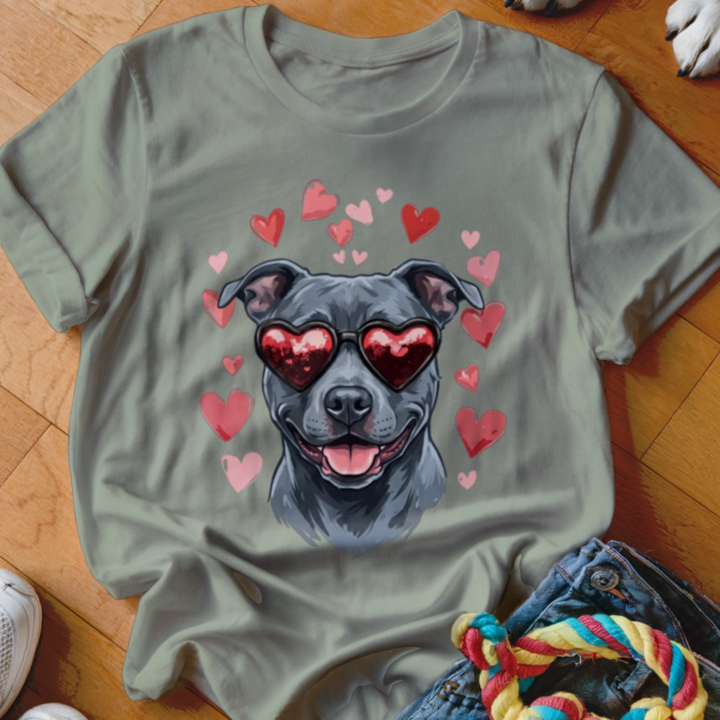 An olive-green t-shirt featuring a graphic of a grey dog wearing heart-shaped sunglasses, surrounded by pink and red hearts.