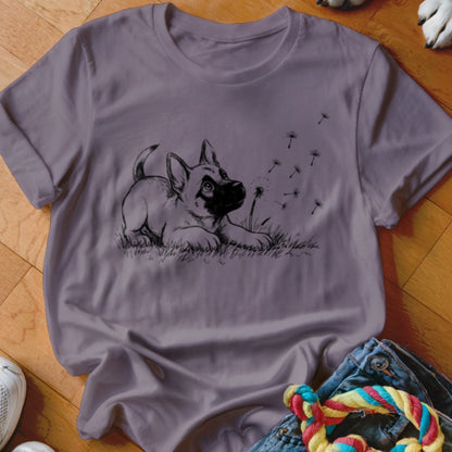 A dusty purple crewneck t-shirt featuring a black sketch of a puppy looking at floating dandelion seeds.