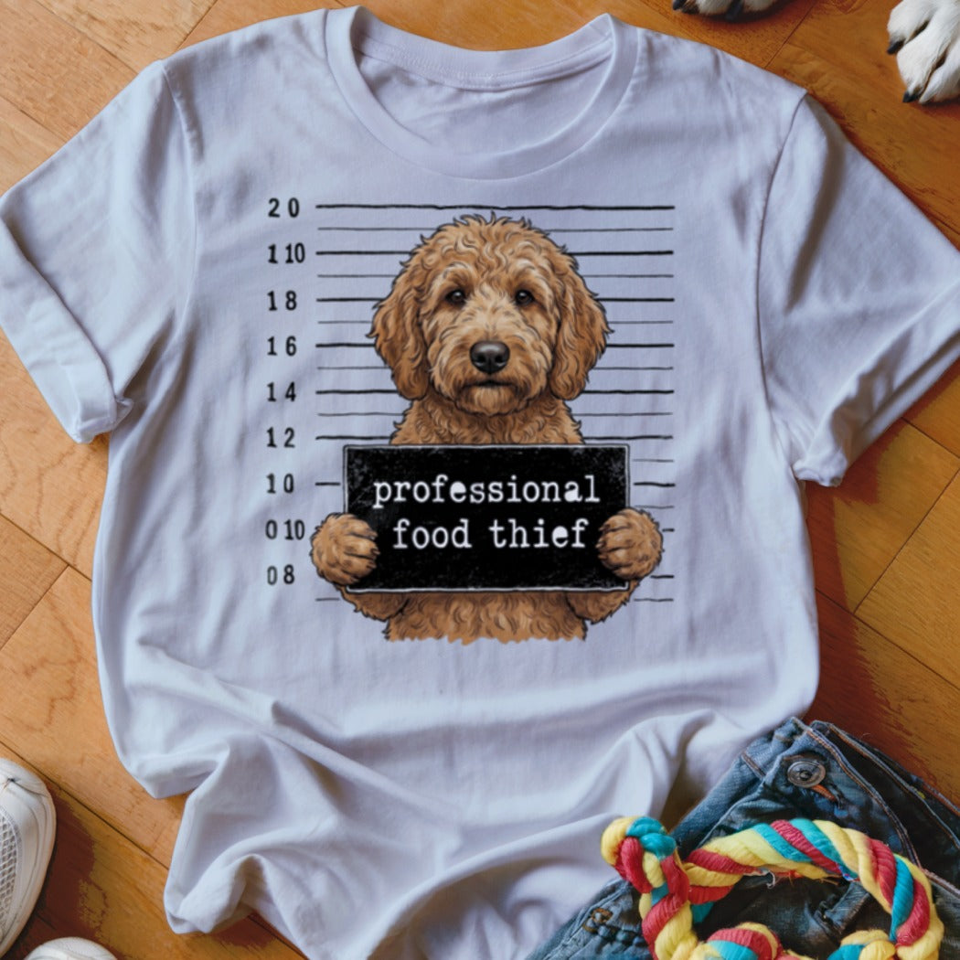 T-shirt graphic of a goldendoodle in a mugshot with "professional food thief" sign.