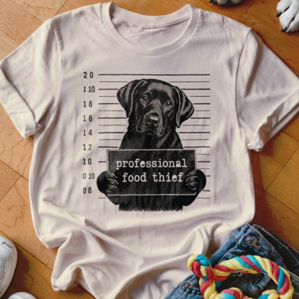 White t-shirt featuring a black lab mugshot with "professional food thief" sign.