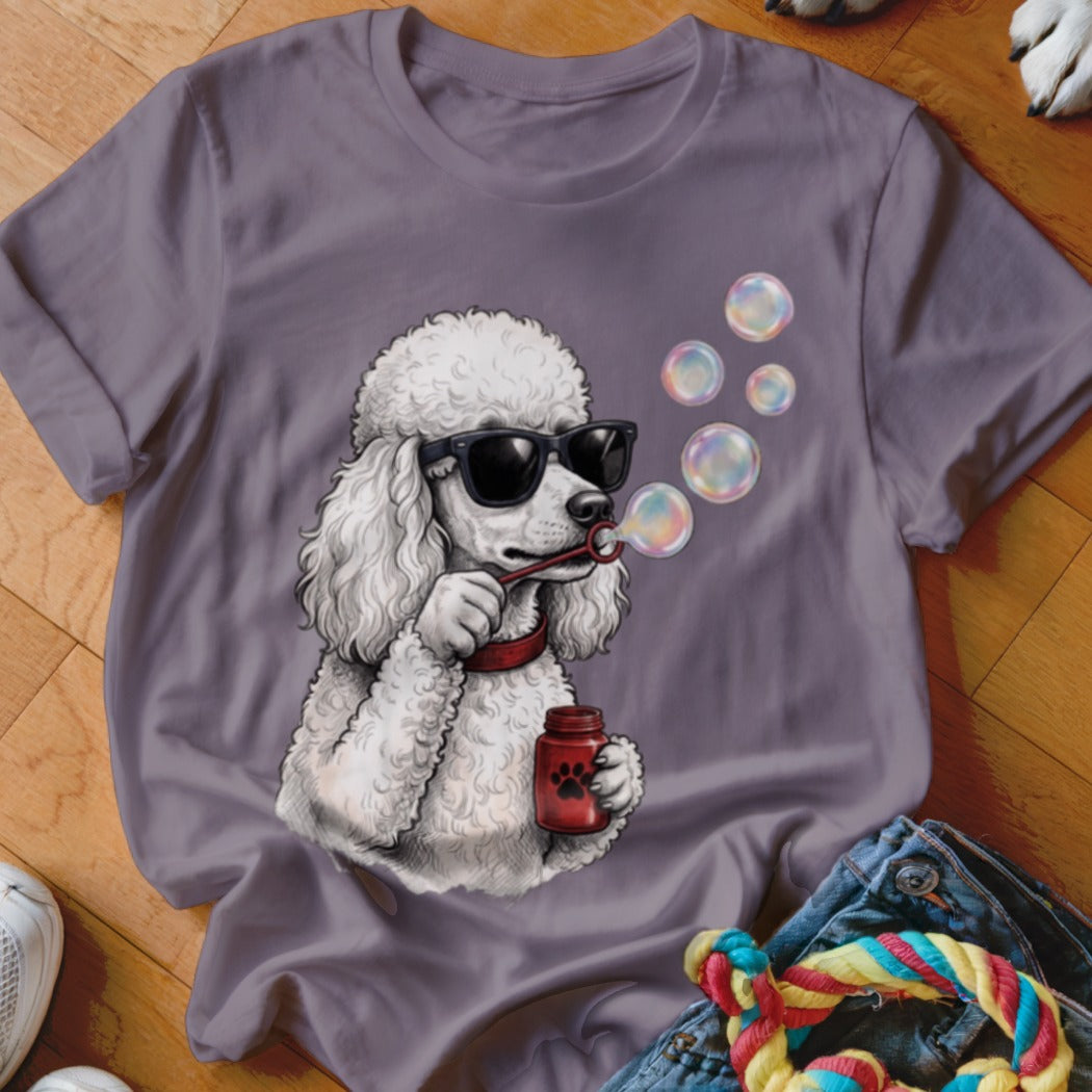 A purple crewneck t-shirt featuring an illustration of a white poodle wearing sunglasses and blowing bubbles.