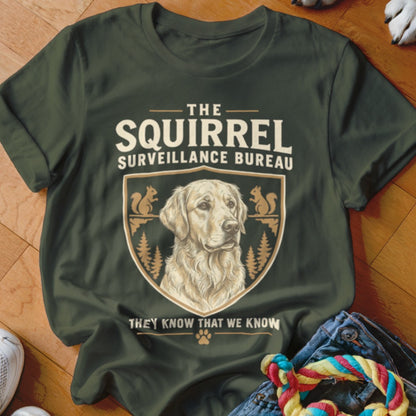 Dark green t-shirt with a vintage-style graphic of a Golden Retriever, squirrels, and text reading The Squirrel Surveillance Bureau.
