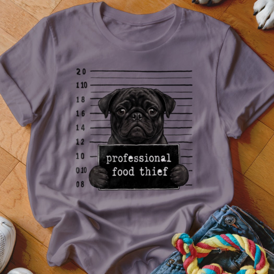 Black pug in mugshot, holding sign that reads "professional food thief".