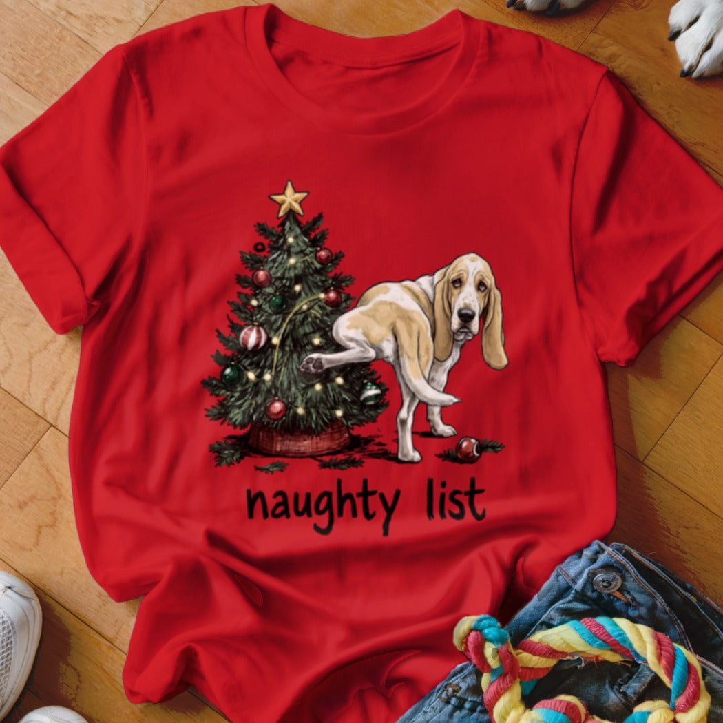 Basset hound lifting leg on Christmas tree with "naughty list" text below.